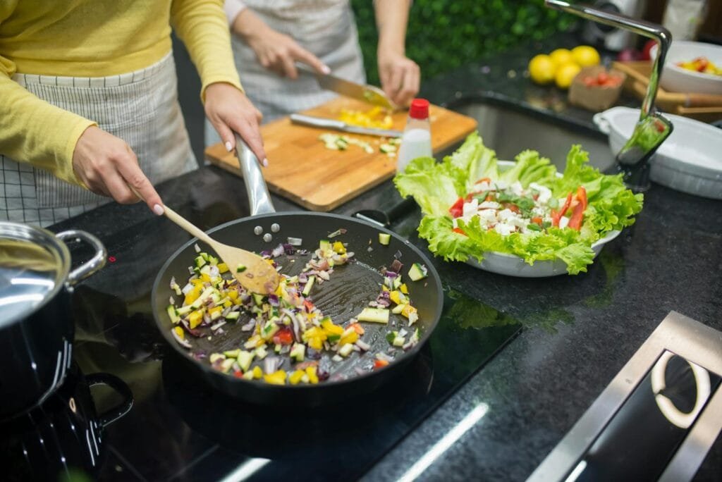 10 Delicious Diabetic-Friendly Recipes You Can Try Today Two adults cooking fresh vegetables on a stove, preparing a healthy meal in a modern kitchen.