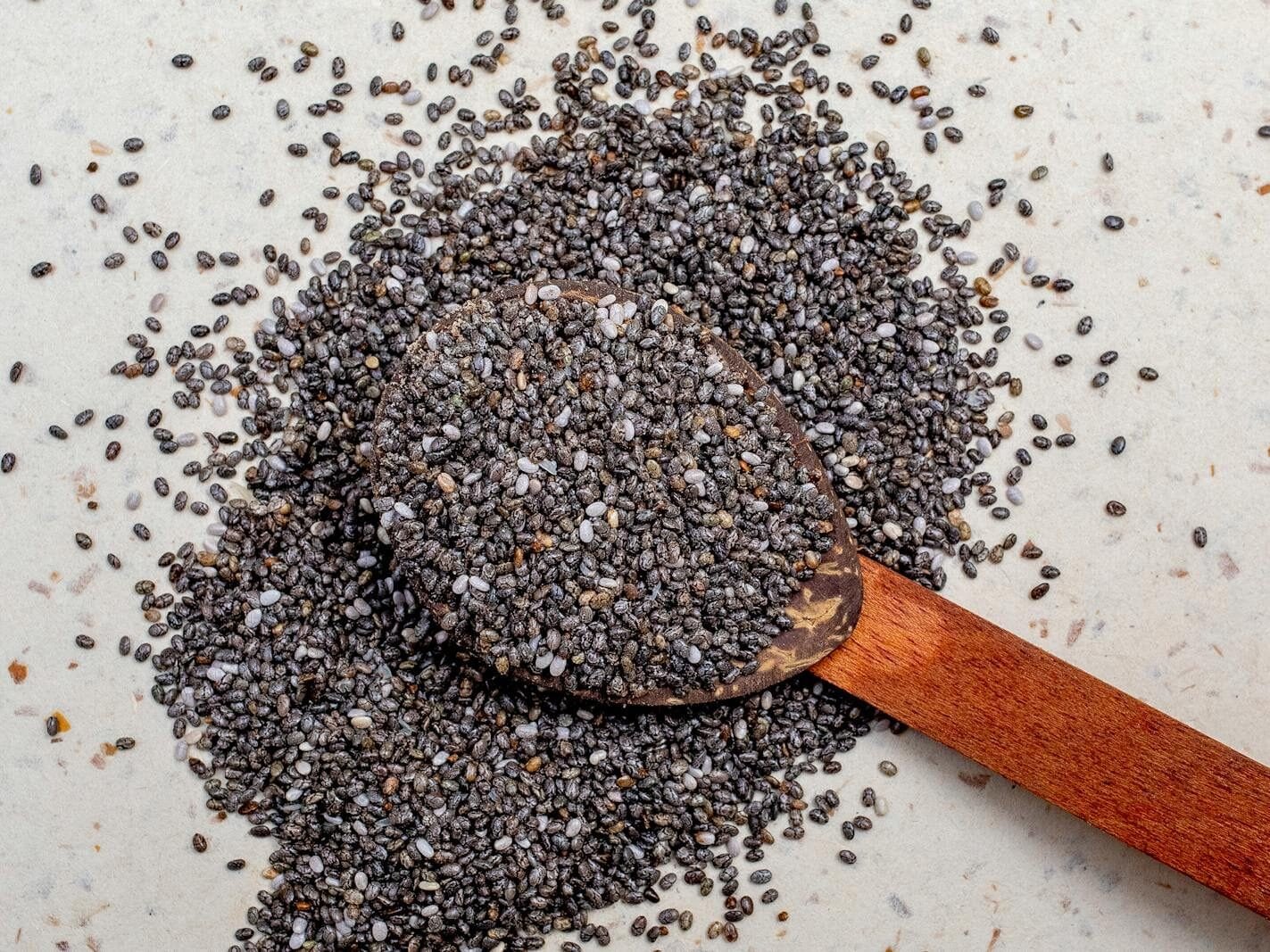 Wooden spoon filled with chia seeds, highlighting their texture and nutritional value.