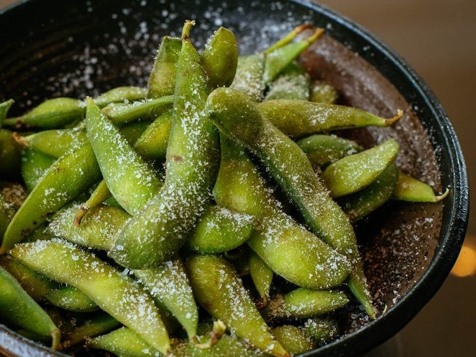 Close-up of fresh salted edamame pods in a black bowl, perfect for appetizer or snack.