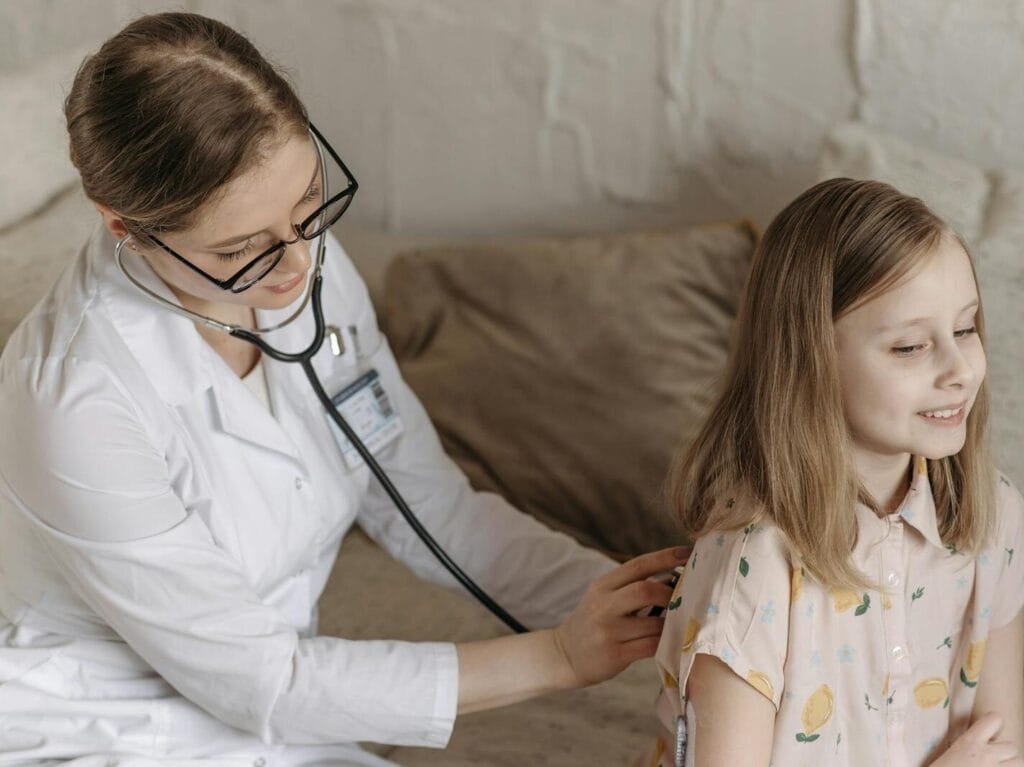 What Is Type 2 Diabetes? Causes, Symptoms And Treatment A doctor with a stethoscope examining a smiling girl during a medical check-up at home.