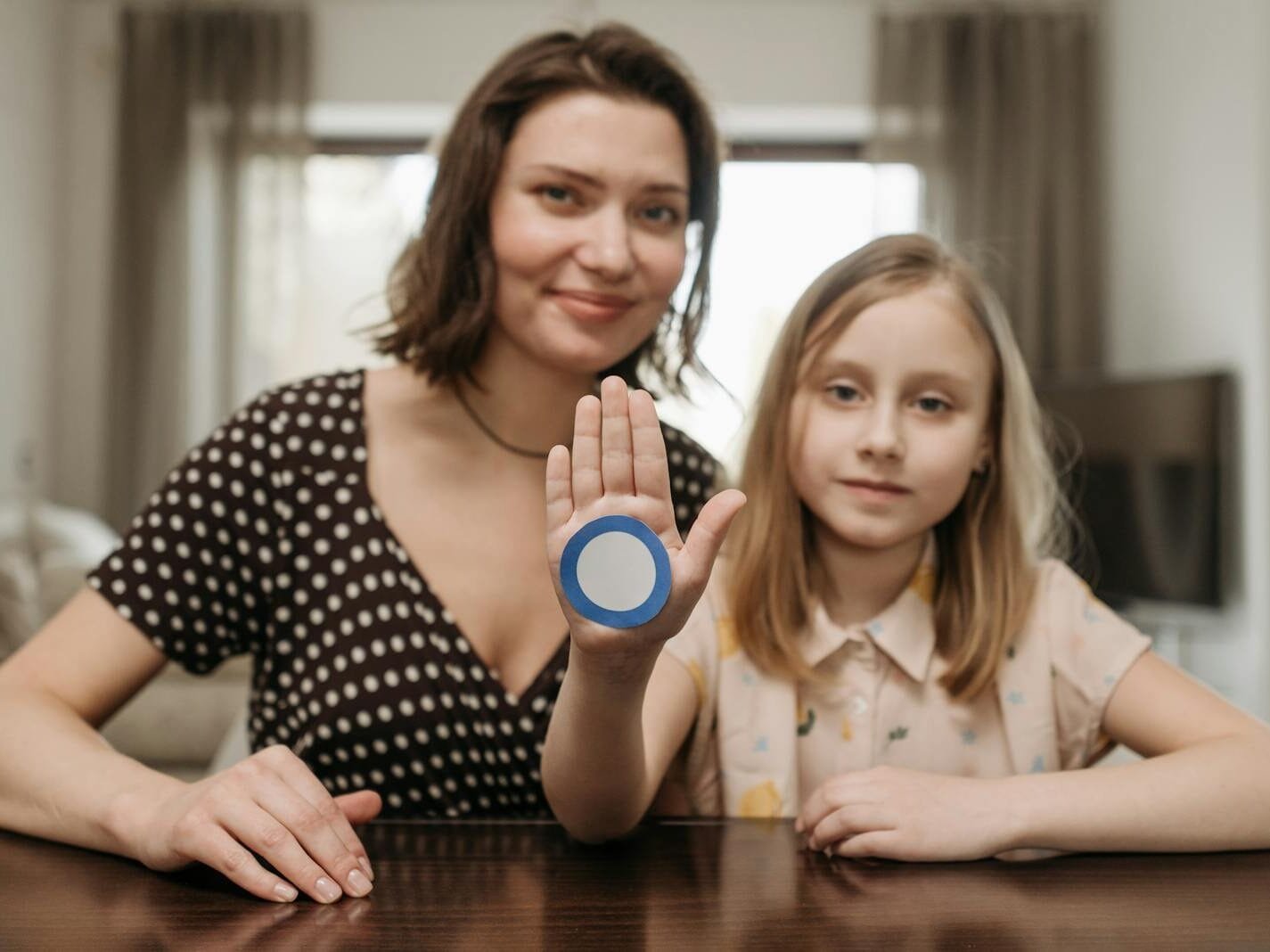 A mother and daughter raise awareness for diabetes with a blue circle symbol indoors.