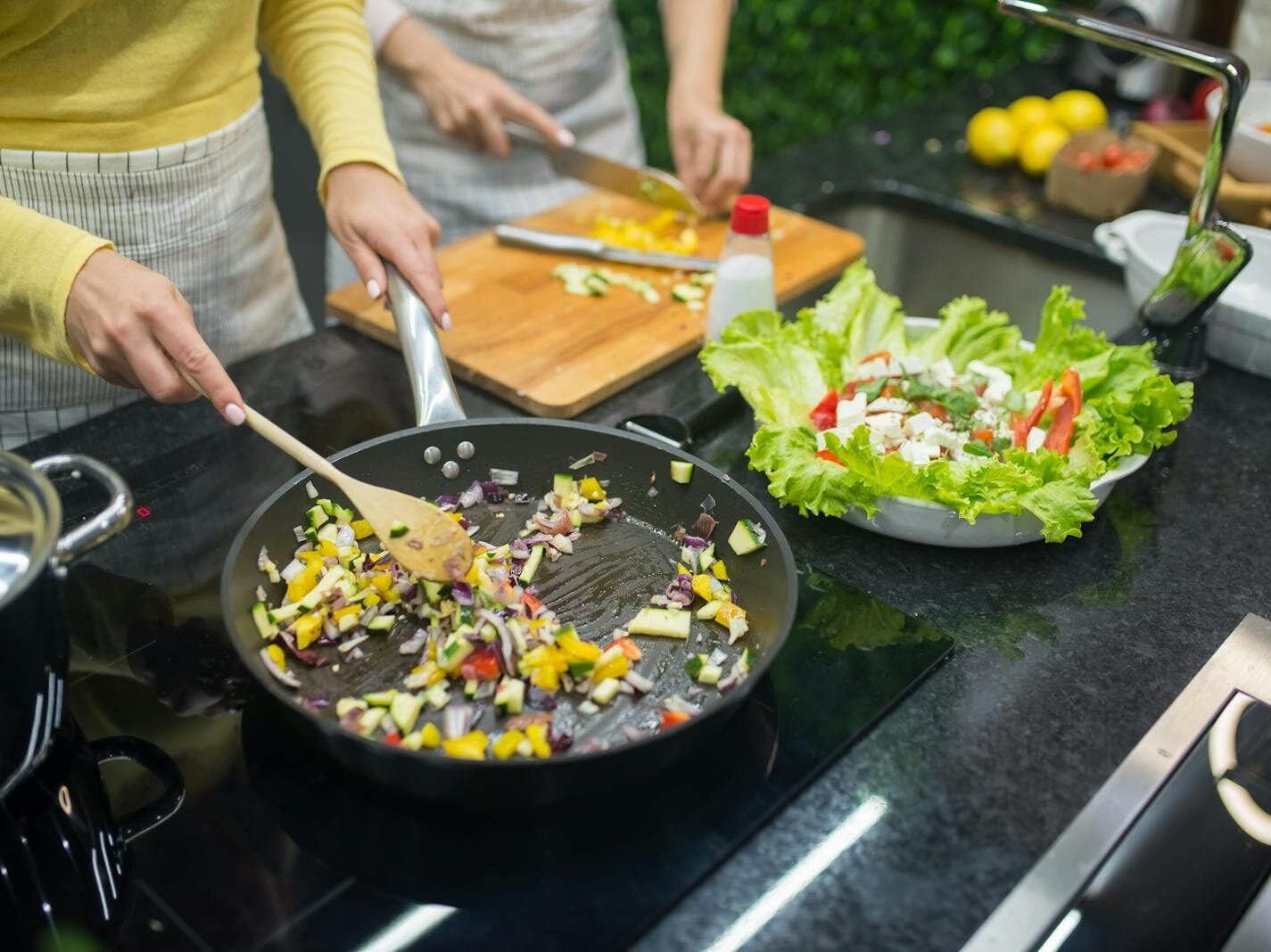 Diabetes Recipes: A Guide To Healthy And Delicious Eating Two adults cooking fresh vegetables on a stove, preparing a healthy meal in a modern kitchen.